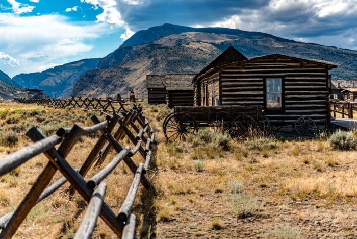 An old western house in a field with mountains in the background Cody
