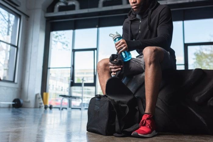 Cropped shot of young african american sportsman holding bottle