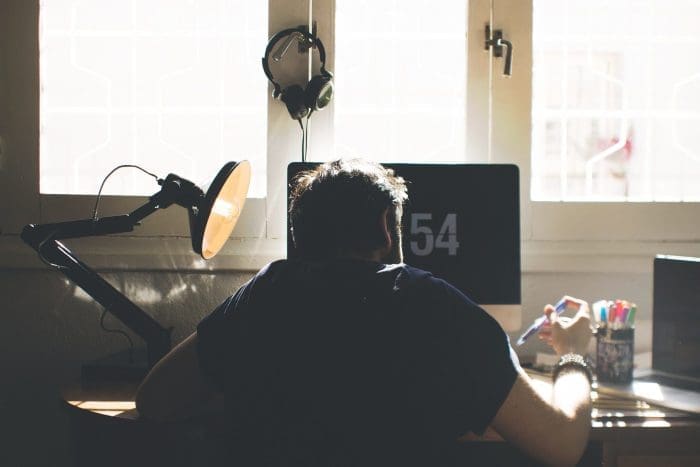 man working at computer desk dim light