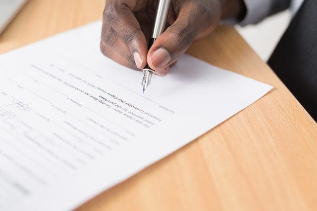 person holding pen writing document
