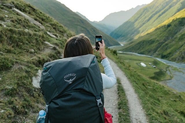 Mountain Backpacker Woman with backpack making photo on iPhone