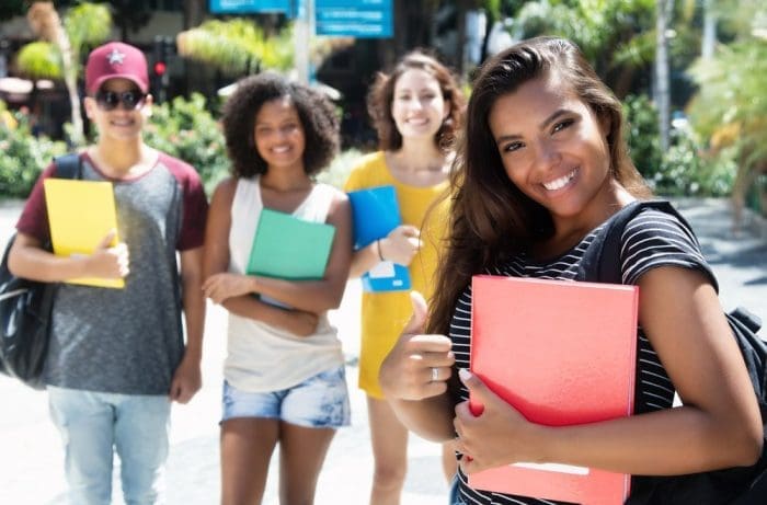 Successful caucasian female student showing thumb with group of international students life Miami