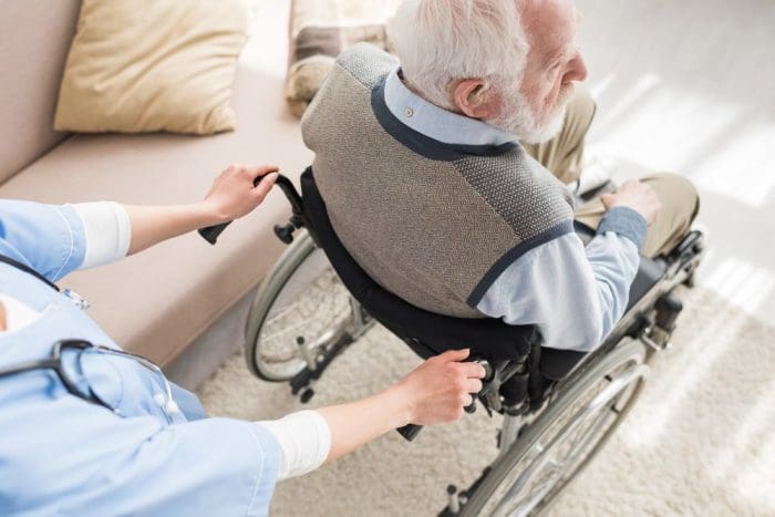 High angle view of nurse standing behind disabled gray haired man
