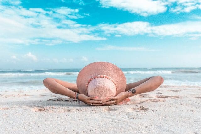 Playa del Carmen, Q.R., México woman relaxing on beach with sun hat