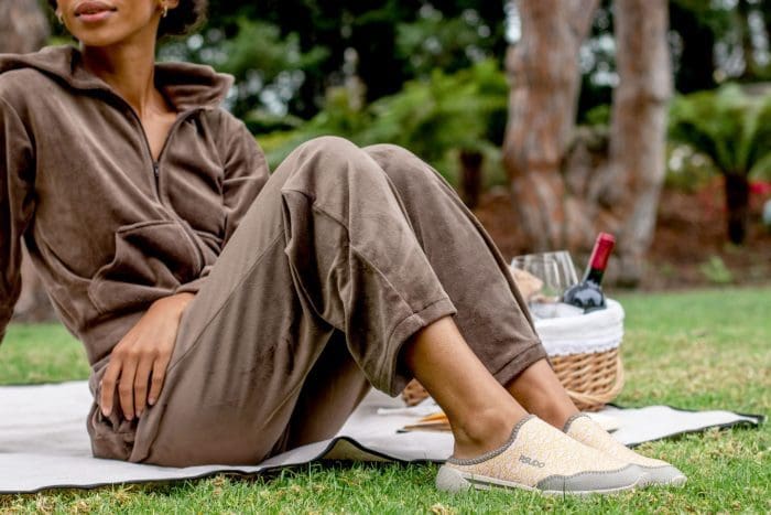 woman sitting in park on picnic blanket wearing sneakers