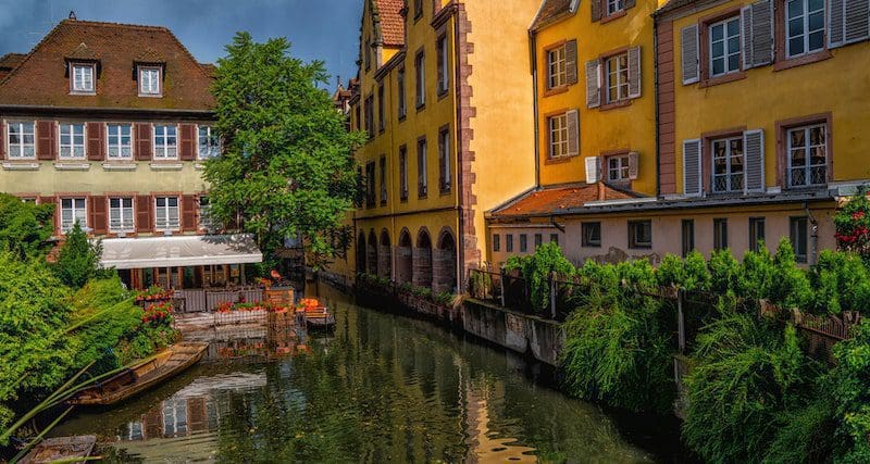View of the historic town of Colmar, also known as Little Venice, with tourists taking a boat ride along traditional colorful houses on idyllic river Lauch, Colmar, Alsace, France