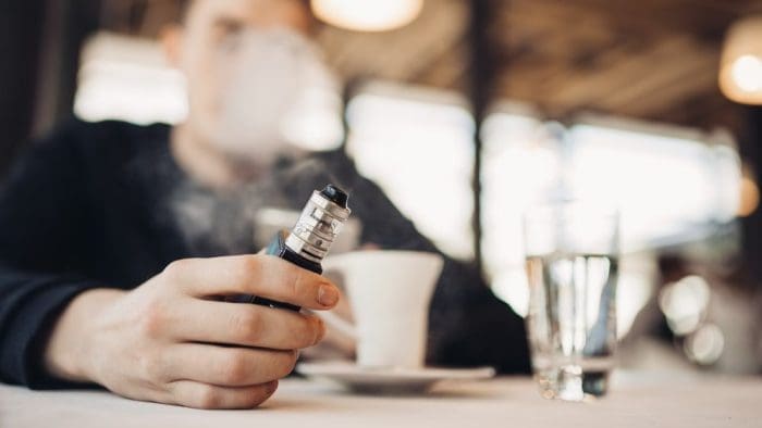 vaping with e cigarette inside at table