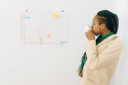 woman drinking coffee looking at line graph