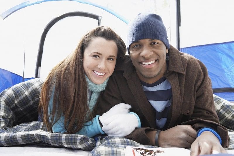 Couple lying in sleeping bags in the tent winter