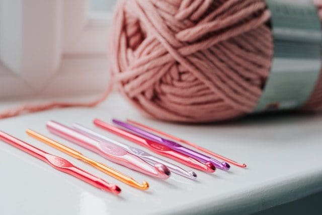 Crochet needles and threads on windowsill