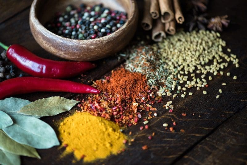 Pepper in bowl with scattered herbs and spices