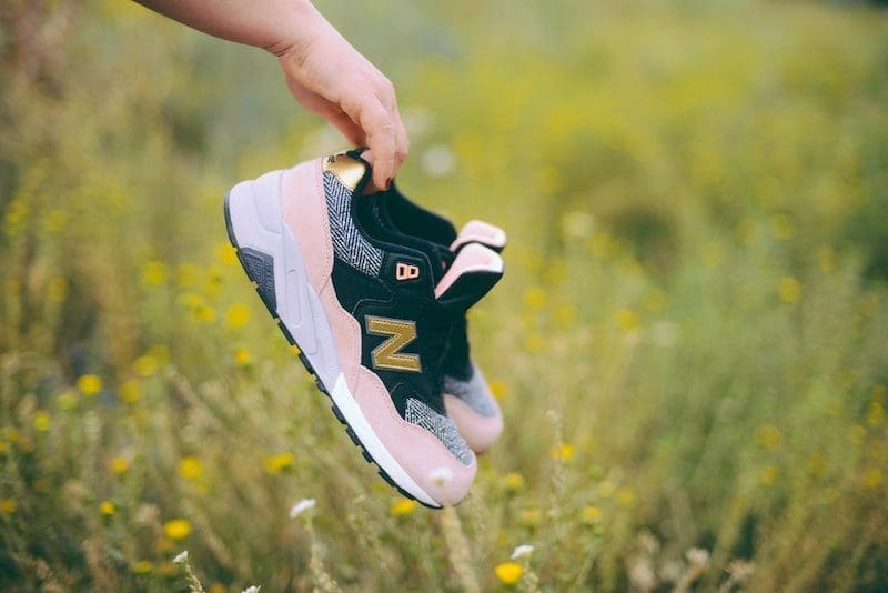 person holding a pair of sneakers over field of grass