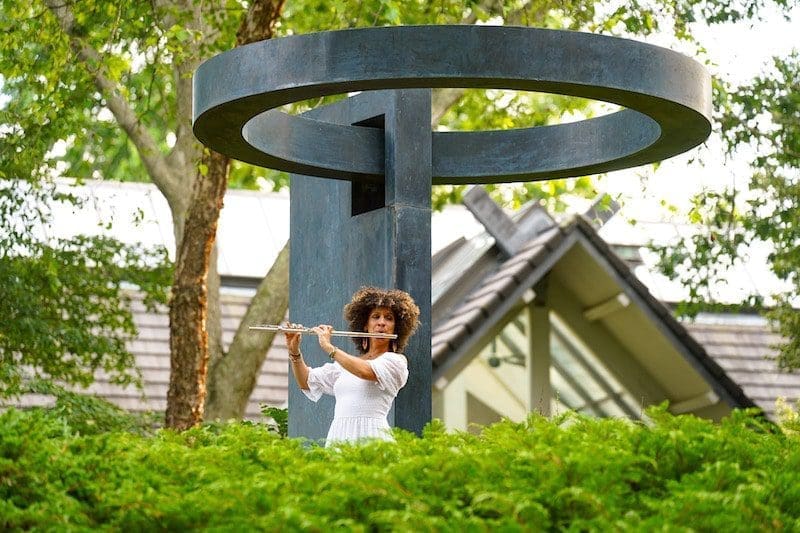 flutist in sculpture garden greenery