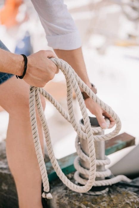 Cropped shot of young man holding rope at seaside