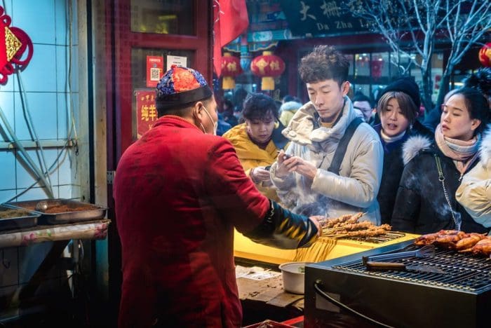Man sells meat sticks in in Dashilan hutong, famous shopping street in Beijing city