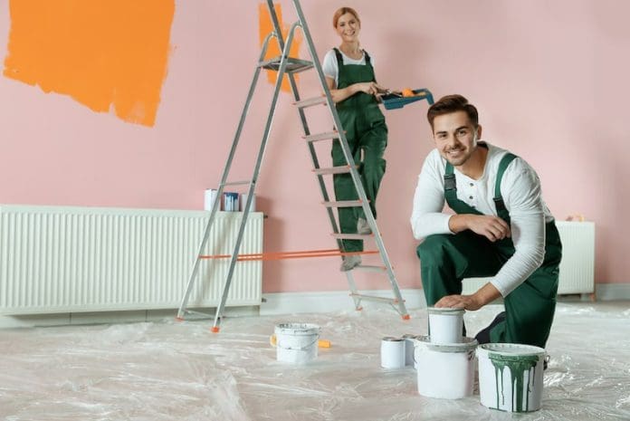 Professional decorators painting wall indoors. Home repair service