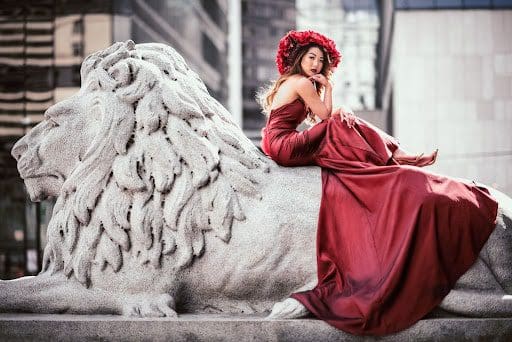 woman in red dress on top of lion statue