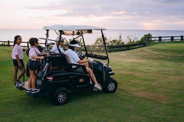 Family Riding a Black Golf Cart on Green Grass