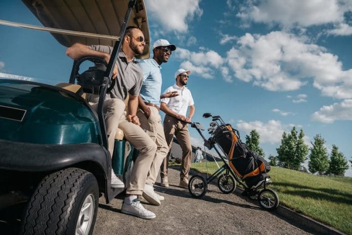 Men standing near golf cart