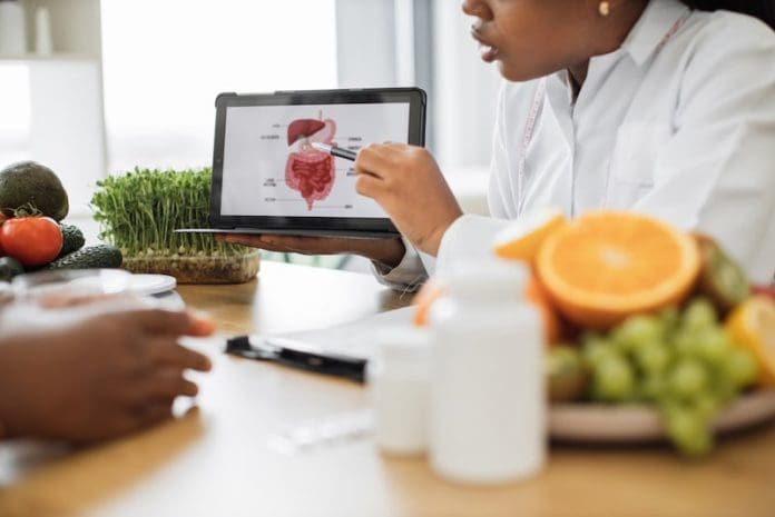 Cropped view of multiracial woman in white coat using tablet