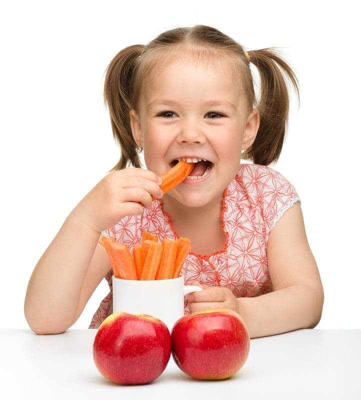 Cute little girl eats carrot and apples