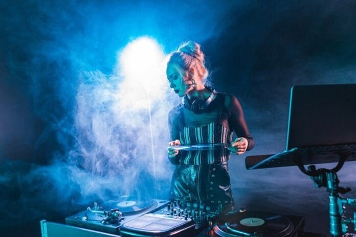 blonde female DJ holding record blue smoke background