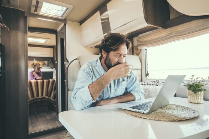 man working on laptop inside luxury camper van