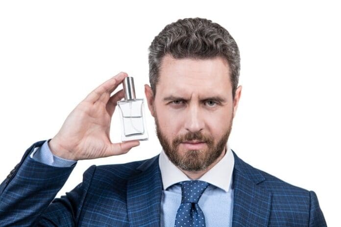 Handsome businessman man in businesslike suit presenting perfume
