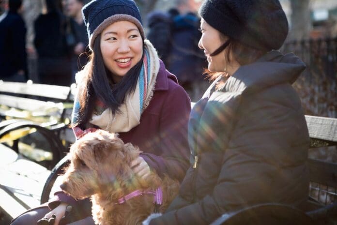 Young asian girls sitting in the park with their dog enjoying