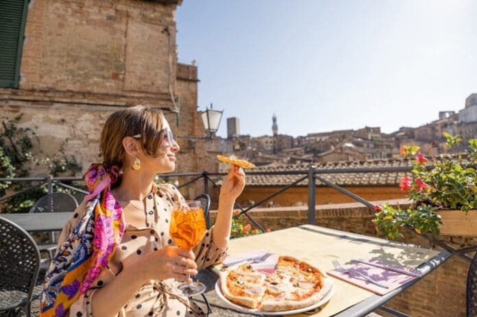 Young woman having lunch with pizza and wine at outdoor