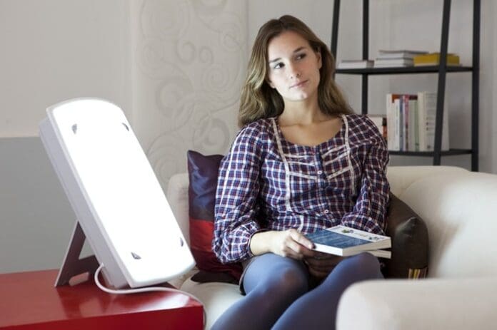 woman reading and using light therapy at home