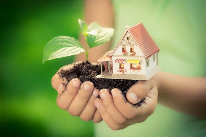 young child holding tiny house in dirt eco friendly