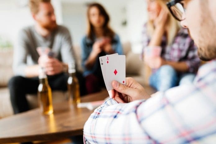 Group of friends having fun while playing cards and drinking
