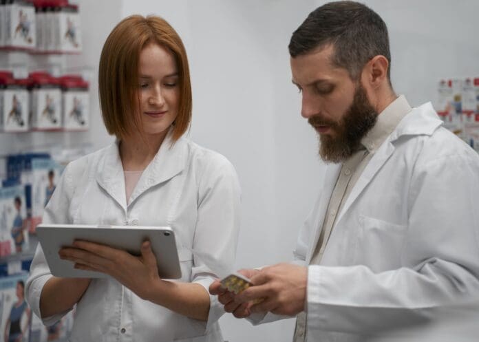 female-pharmacist-training-male-coworker-with-tablet-pharmacy