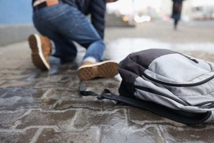 Man with backpack felling on slippery sidewalk in winter