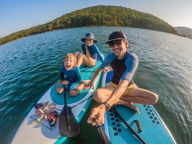 family on paddleboard taking selfie