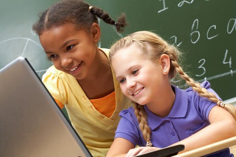 girls learning at computer chalkboard math