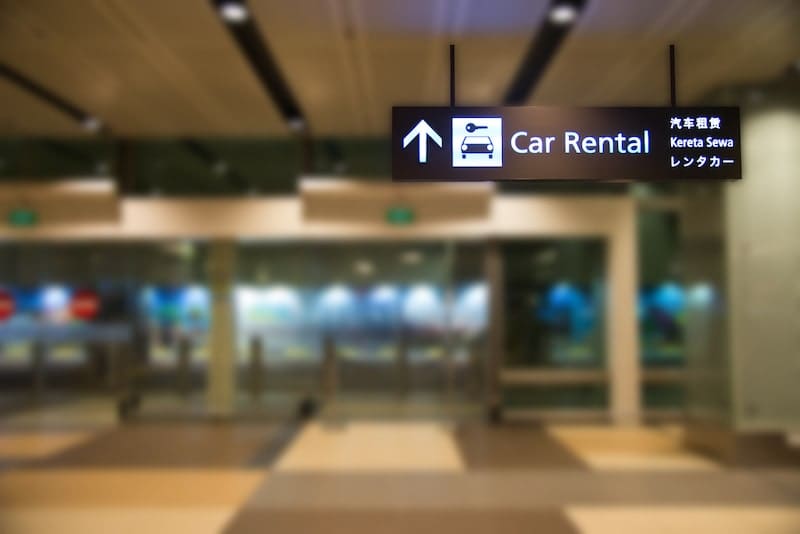 Blue illuminated rental car sign with blur background