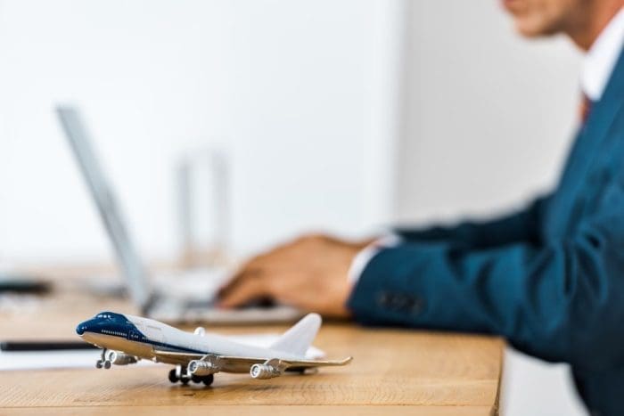 Toy airplane at wooden table with office worker using laptop
