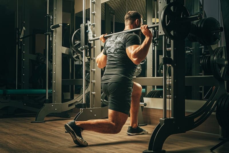 Fit man doing squats in a training machine-min