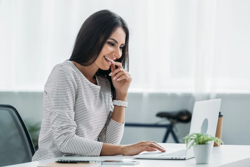 Beautiful and brunette woman smiling and looking at screen