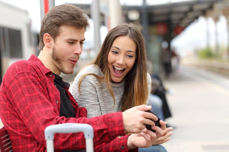 Couple playing games with a smart phone in a train station