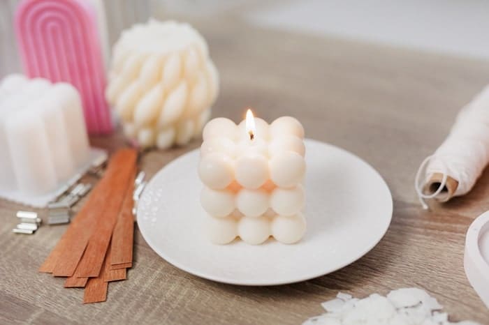 Burning beautiful white bauble candle on ceramic stand