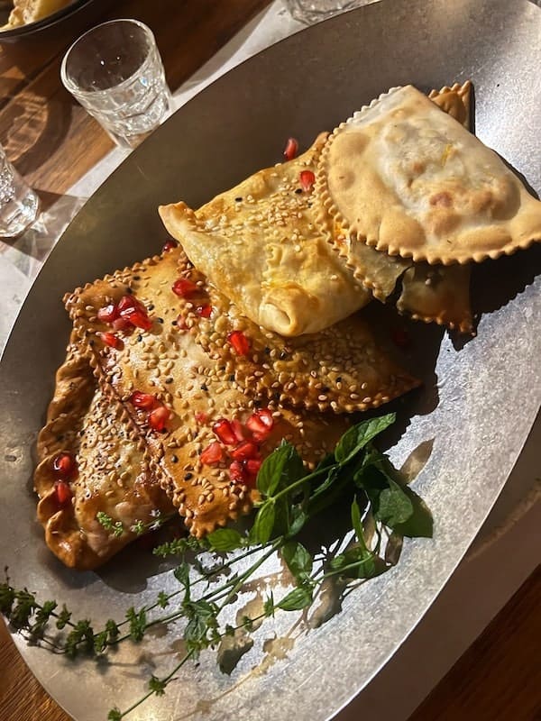 Cretan pastry flaky dough, sesame seeds, and pomegranate garnish