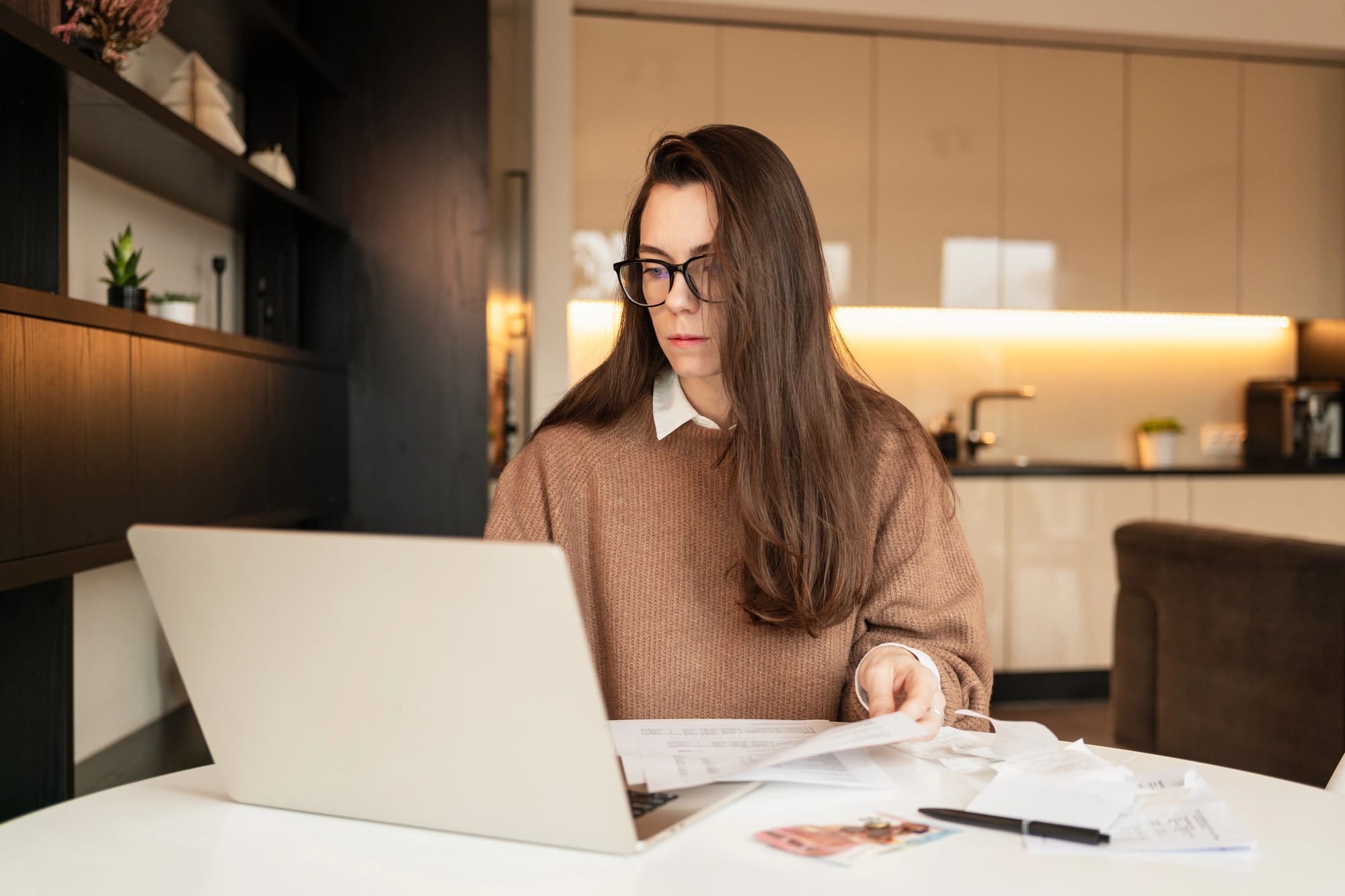Woman with long brown hair paying bills at home using the laptop